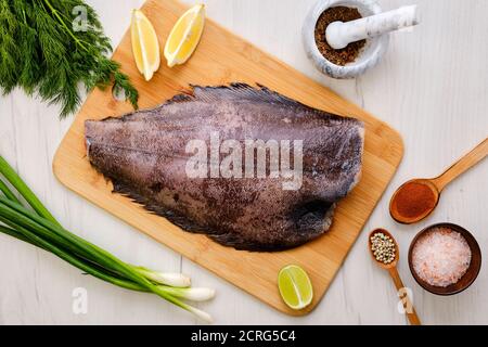 Vista dall'alto dell'halibut fresco grezzo senza testa in legno tagliere Foto Stock