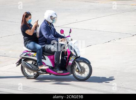 SAMUT PRAKAN, THAILANDIA, 23 2020 LUGLIO, donna guida una moto come passeggero e guarda nel telefono cellulare. Foto Stock