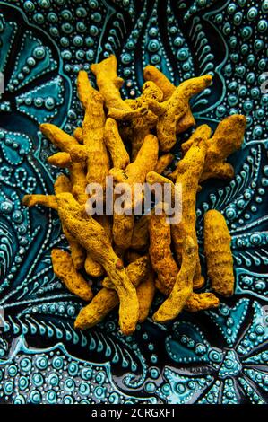 Radici curcuma secche intere su piastra in ceramica Foto Stock