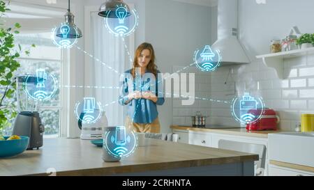 Internet of Things Concept: Giovane donna che usa lo smartphone in cucina. Controlla i suoi elettrodomestici per la cucina con IOT. Grafica che mostra la digitalizzazione Vis Foto Stock