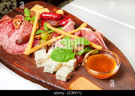 Formaggi assortiti e prelibatezze di carne su tavola di legno. Primo piano, messa a fuoco selettiva Foto Stock
