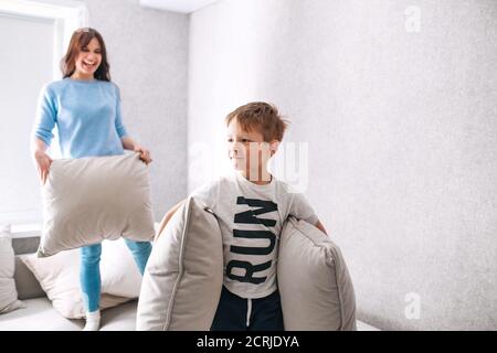 Figlio e madre che hanno una lotta cuscino la mattina soleggiata a casa Foto Stock