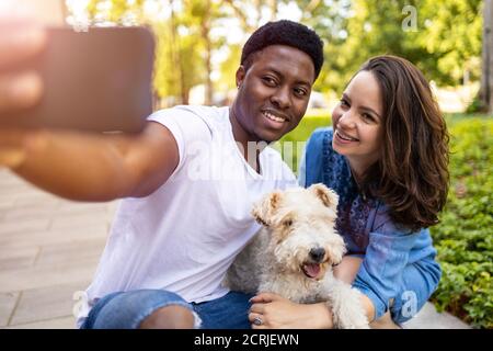 Felice giovane coppia con il loro cane animale domestico all'aperto Foto Stock