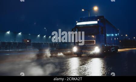 Blue Long Haul semi-Truck con Cargo Trailer Full of Goods viaggia di notte sulla Freeway Road, guidando attraverso il Continente attraverso pioggia, nebbia, neve Foto Stock