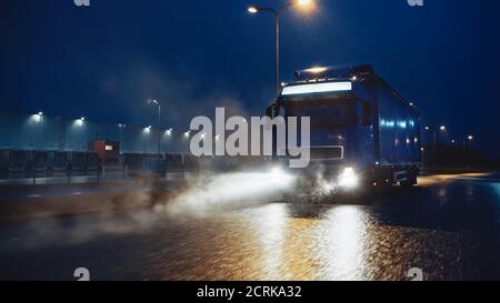 Blue Long Haul semi-Truck con Cargo Trailer Full of Goods viaggia di notte sulla Freeway Road, guidando attraverso il Continente attraverso pioggia, nebbia, neve Foto Stock