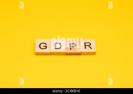 Regolamento generale sulla protezione dei dati. Lettere che scrivano il GDPR fatto da blocchi di legno su sfondo giallo Foto Stock