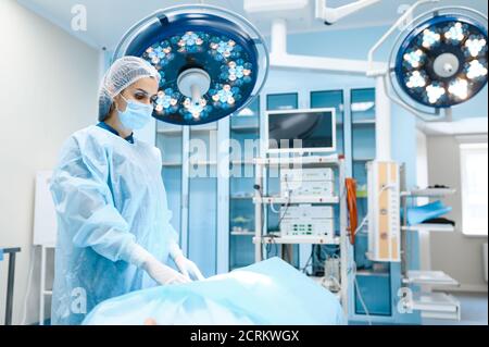 Chirurgo femminile in abito e maschera in sala operatoria Foto Stock