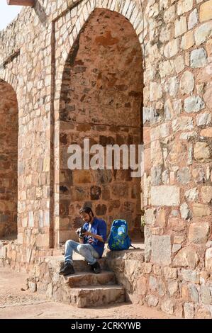 Un ragazzo indiano che siede e scattando l'immagine del vecchio forte che dà la posa per sparare di moda. Foto Stock