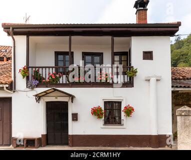 Casa bianca tradizionale con fiori decorativi in geranio, tipica della Spagna. Balcone e finestre in legno. Fiori colorati. Camino sul tetto. Astur Foto Stock