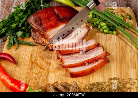 la carne affumicata si trova sulla tavola con erbe e salsa Foto Stock