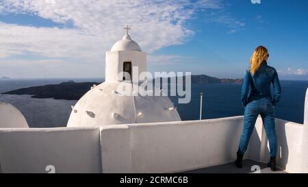 Una bella ragazza che osserva il panorama meraviglioso da una terrazza a Santorini, Grecia Foto Stock