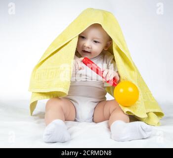 Foto di un bambino di undici mesi con sonaglino e asciugamano Foto Stock