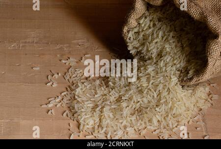 mucchio di grano di riso su pavimento di legno in una iuta borsa Foto Stock