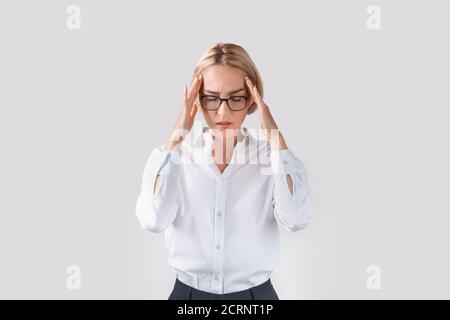 Stanco dipendente di ufficio che soffre di mal di testa su sfondo studio chiaro Foto Stock