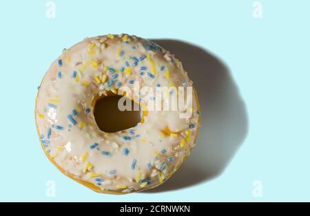 Primo piano vista della ciambella cosparsa di smalto multicolore isolato su sfondo blu. Concetto di cibo e bevande. Foto Stock