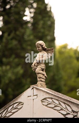 Piccola statua di un piccolo angelo ragazzo con le ali alla lapide presso il vecchio cimitero in Dalmazia, Croazia, primo piano Foto Stock