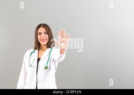 Bella sorridente turco donna medico ritratto in studio è fiducioso umore, è gesturing alto cinque Foto Stock