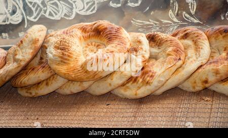 Tipico pane piatto con crosta croccante appena sfornato in tandoor sul mercato mostra di vecchia panetteria. Pane fresco al gusto di yammy da tandoor di creta per la vendita. Foto Stock