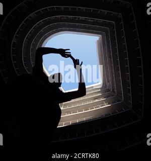 Fotografo in grande città. Uomo che fa una foto sul cellulare in città. Moderno edificio rotondo con cielo blu sulla sommita'. Silhouette di un uomo che prende il Foto Stock