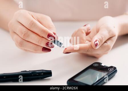 Donna che controlla il livello di zucchero nel sangue. Concetto di assistenza sanitaria per il diabete Foto Stock