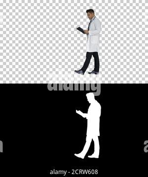 Medico concentrato che legge la documentazione mentre cammina, Foto Stock