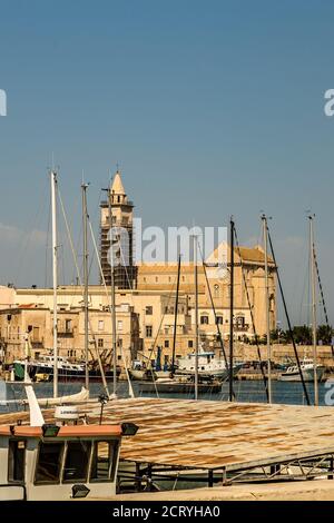 TRANI (BT), 30 AGOSTO 2020: La luce illumina la Cattedrale di Santa Maria Assunta mentre le barche ormeggiate galleggiano nel porto di Trani Foto Stock