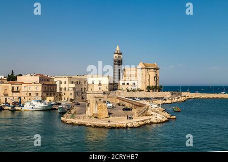 TRANI (BT), 30 AGOSTO 2020: La luce illumina la Cattedrale di Santa Maria Assunta mentre le barche ormeggiate galleggiano nel porto di Trani Foto Stock