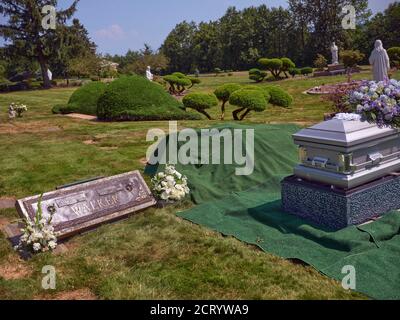 Accanto ad una gravesite si trova una casetta con fiori pronta per la sepoltura. Foto Stock