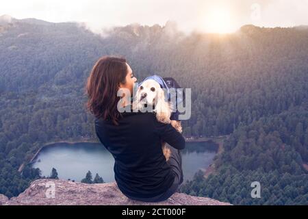 Donna messicana con animale domestico (cocker spaniel) guardando alba in montagna Foto Stock