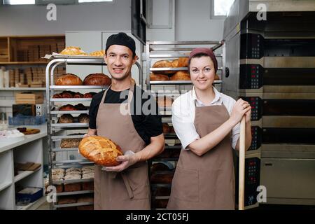 Due panettieri, maschio e femmina in posa per una foto in una cucina da forno Foto Stock