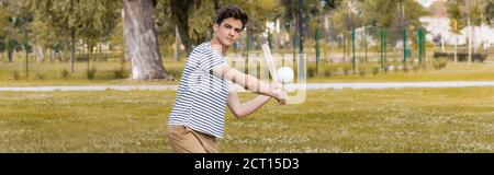 colpo panoramico del ragazzo teenager che tiene il bat di softball e che gioca baseball nel parco Foto Stock