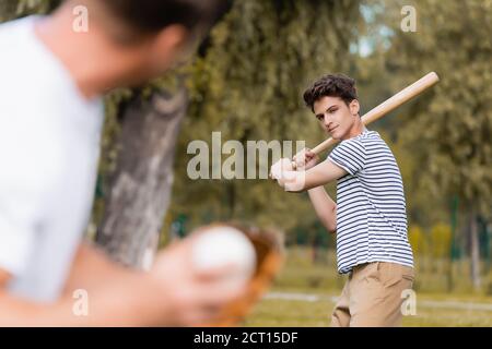 fuoco selettivo di figlio adolescente concentrato con softball bat giocare baseball con padre nel parco Foto Stock