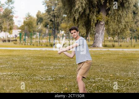 ragazzo adolescente che tiene la mazza di softball e che gioca a baseball nel parco Foto Stock