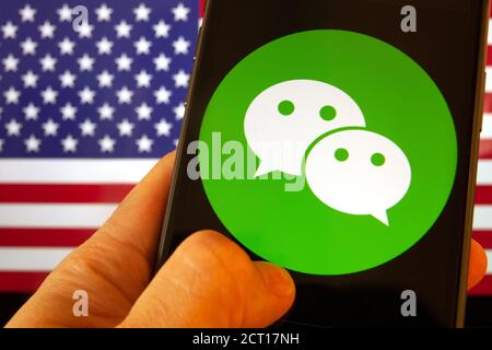 Cellulare con icona WeChat davanti alla bandiera d'America. il presidente degli Stati Uniti Donald Trump vieta le applicazioni della Cina a causa della sicurezza nazionale Foto Stock