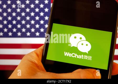 Cellulare con icona WeChat davanti alla bandiera d'America. il presidente degli Stati Uniti Donald Trump vieta le applicazioni della Cina a causa della sicurezza nazionale Foto Stock