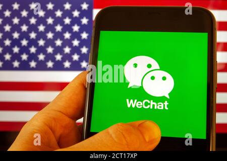 Cellulare con icona WeChat davanti alla bandiera d'America. il presidente degli Stati Uniti Donald Trump vieta le applicazioni della Cina a causa della sicurezza nazionale Foto Stock