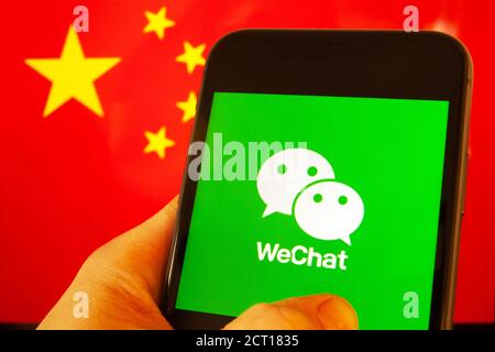 Cellulare con logo WeChat davanti alla bandiera della Cina. il presidente degli Stati Uniti Donald Trump vieta le applicazioni della Cina a causa della minaccia per la sicurezza nazionale. Foto Stock