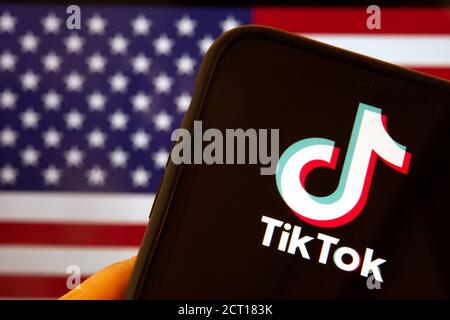 Cellulare con logo TikTok davanti alla bandiera d'America. il presidente degli Stati Uniti Donald Trump vieta le applicazioni della Cina a causa della minaccia per la sicurezza nazionale. Foto Stock