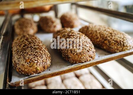 Loafs di pane appena sfornati, ricoperti di semi che si raffreddano un ripiano in ferro Foto Stock