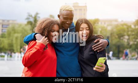 Multi etnia amici esterni guardare lo schermo dello smartphone. Diverse persone di gruppo Afro american asian trascorrere il tempo insieme multirazziale maschio studien femmina Foto Stock