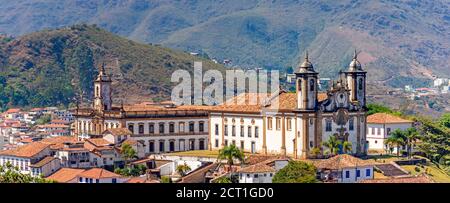 Vista panoramica dalla cima del centro storico di Ouro Preto con le sue case, la chiesa, i monumenti e le montagne Foto Stock