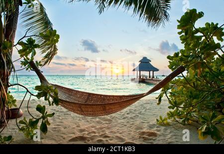 Amaca vuota nella spiaggia tropicale nelle Maldive a. tramonto Foto Stock