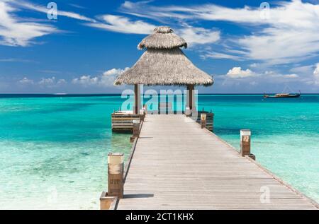 Pontile in legno sul bellissimo mare maldiviano con cielo blu Foto Stock