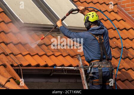 operatore che lava il tetto con acqua pressurizzata Foto Stock