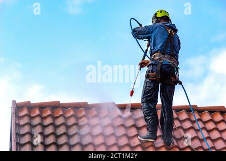 operatore che lava il tetto con acqua pressurizzata Foto Stock
