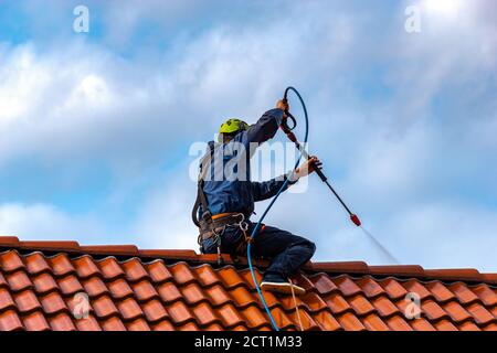 operatore che lava il tetto con acqua pressurizzata Foto Stock