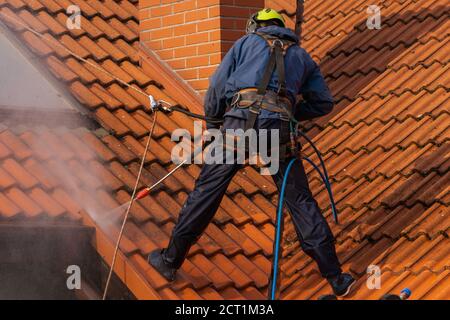 operatore che lava il tetto con acqua pressurizzata Foto Stock