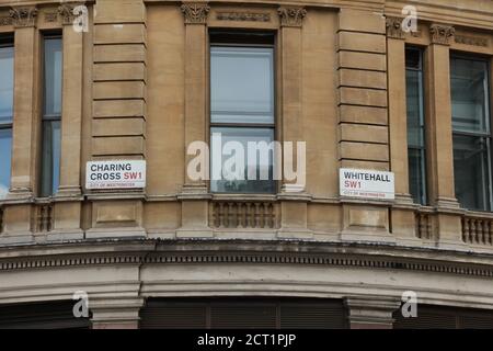 Due cartelli stradali visti insieme sono fissati in alto contro un muro all'aperto all'intersezione di Charing Cross e Whitehall, Londra, Regno Unito. Foto Stock