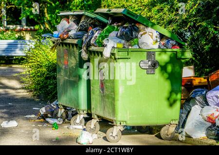 contenitori di rifiuti di plastica verdi affollati in città Foto Stock