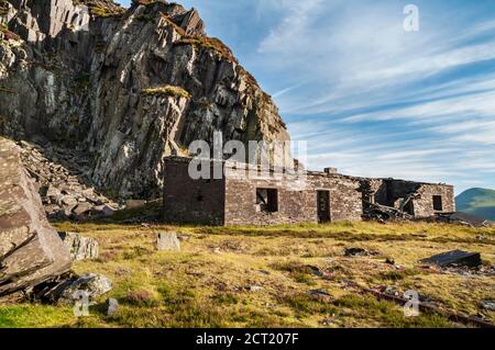 Edifici abbandonati sotto una faccia a strapiombo nella cava di ardesia Dinorwic Nel Galles del Nord Foto Stock